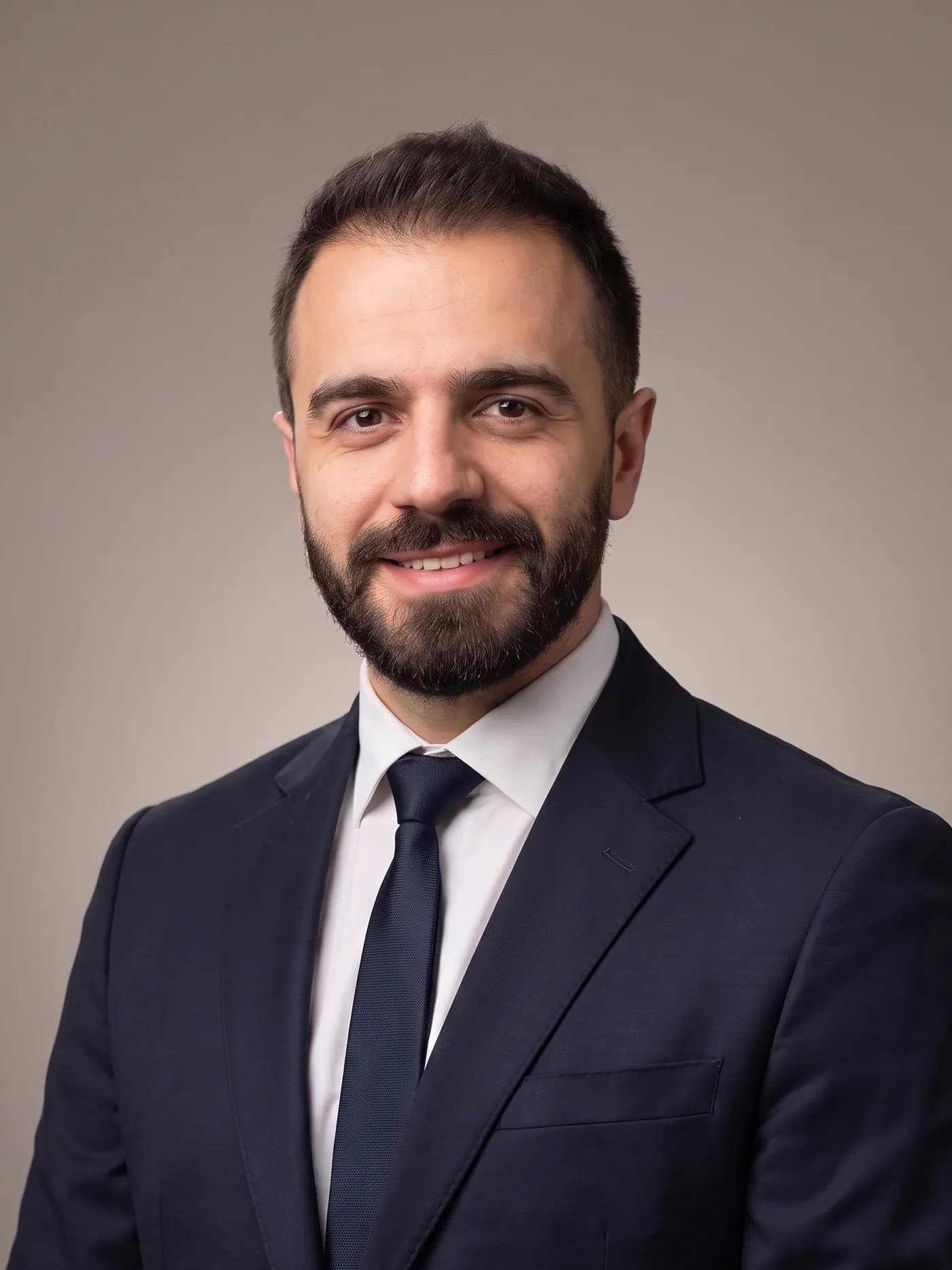 Selami Sefa Şık, lacivert takım elbiseyle stüdyoda çekilmiş omuz hizası portre
